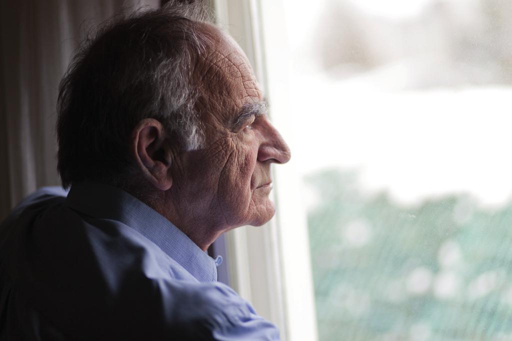 a depressed lonely old man looking out of the window