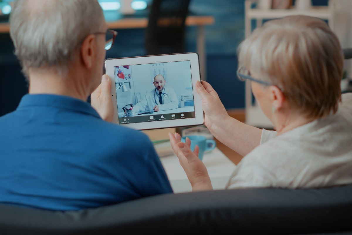 senior couple telehealth with online doctor with tablet